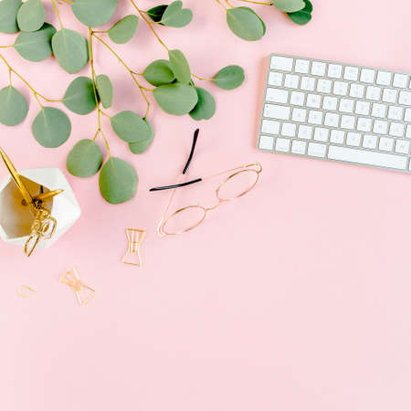Office table desk with computer, green leaves eucalyptus, clipboard, golden accessories, diary, glasses. Magazines, social media. Top view. Flat lay.の写真素材
