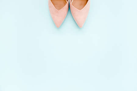 Pastel pink women high heel shoes on blue background. Flat lay, top view trendy fashion feminine...