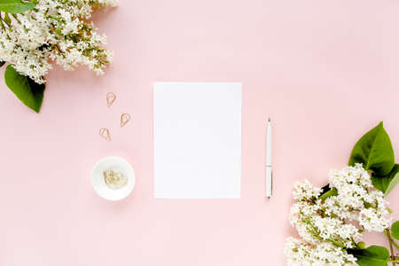 Top view office desk. Workspace with, paper blank, lilac on pink background. Flat composition for...