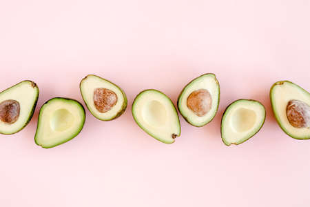 Avocado on pink background. Tropical abstract background with avocado. Food concept. flat lay, top viewの写真素材