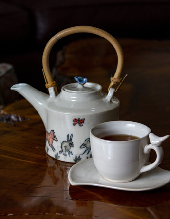Animal-decorated teapot and cup of hot teaの写真素材
