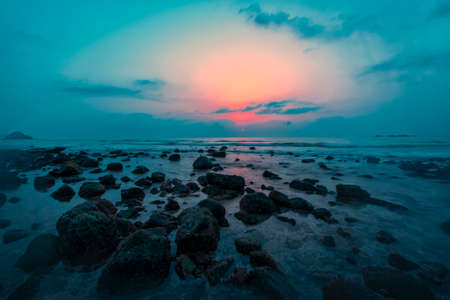Sun rise at the beach with stones and rocksの写真素材