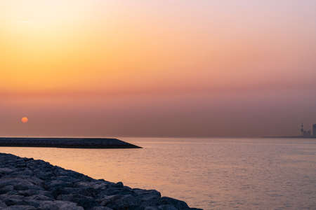 Sun rise at the beach with water and sun with bridgeの写真素材