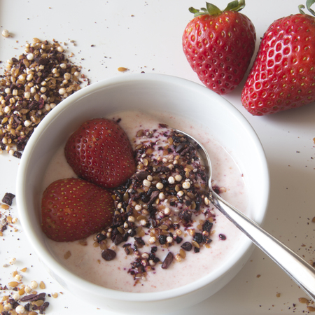 Greek strawberry yoghurt served in a bowl with strawberries and a superfruit topping of dried blueberries, hibiscus, chia seeds and airy quinoa popsの写真素材