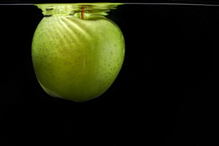 green apple in water on black backgroundの写真素材