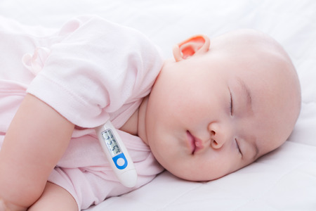 Close-up newborn baby sleeping with digital mercury thermometerの写真素材