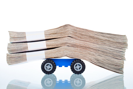 Stacks of banknotes on toy car wheels,on white backgroundの写真素材