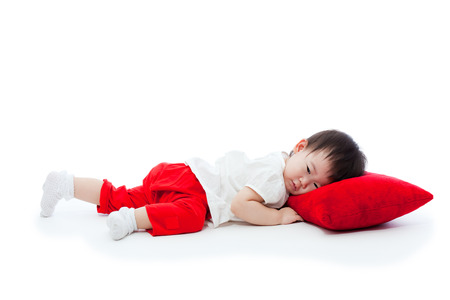 Cute little asian girl   lying on a red pillow, on white background, shot in studioの写真素材