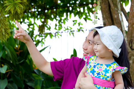 Young asian woman and cute little daughter  smiling happily in the backyard,mother pointing upの写真素材