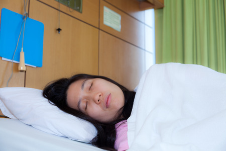 Asian woman patient lying on a sickbed in hospital wardの写真素材