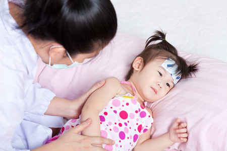 Lady doctor touching arm little asian girl,girl lying on sickbedの写真素材