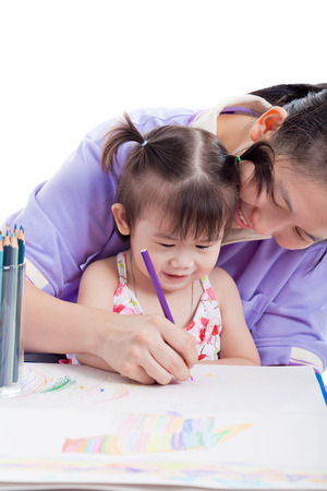 Portrait of woman and little asian girl drawing, painting and smiling together, mother teaches her daughter to draw with colour pencils , isolated on white backgroundの写真素材