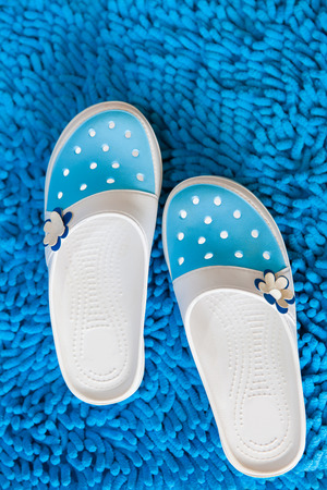 A pair of slippers lay on blue rugの写真素材