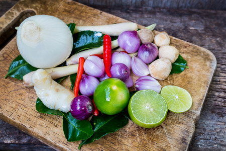 Still life kaffir lime leaf, lemon, lemongrass, galangal, chili, onions and Straw mushroom herb and spicy ingredients Thai food (tom yum)over chopping block on wood background.の写真素材