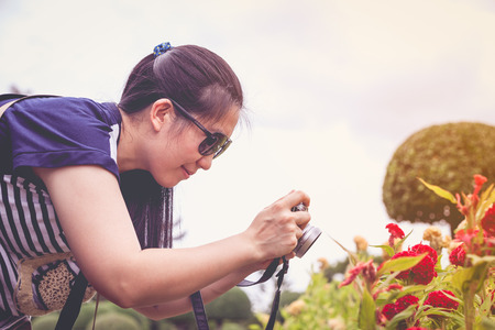 Female photographer with sunglasses holding professional digital camera. Asian woman taking...