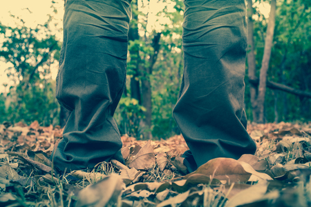 Close up man's legs standing on dry leaves, nature background, shallow depth of field (dof), selective focus. Vintage picture style.の写真素材