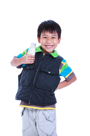Fun portrait of handsome asian boy smiling and holding bottle of milk. Drinking milk for good health. Child looking at camera, isolated on white background. Studio shoot.の写真素材