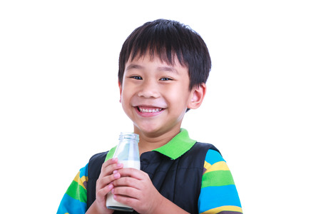 Close up. Fun portrait of handsome asian boy smiling and holding bottle of milk. Drinking milk for good health. Child looking at camera, isolated on white background. Studio shoot.の写真素材