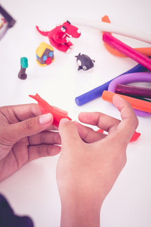 Child playing and creating toys from play dough. Child molding modeling clay. Strengthen the imagination of child. Vintage picture style.の写真素材