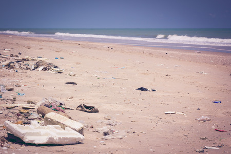 Pollution on the beach of tropical sea. Plastic garbage, foam, rubbish and dirty waste on beach in summer day. The sky above is a perfect blue color. Outdoors. Vintage picture style.の写真素材