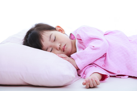 Healthy children concept. Close up of little asian child sleeping peacefully. Adorable girl in pink pajamas taking a nap.の写真素材