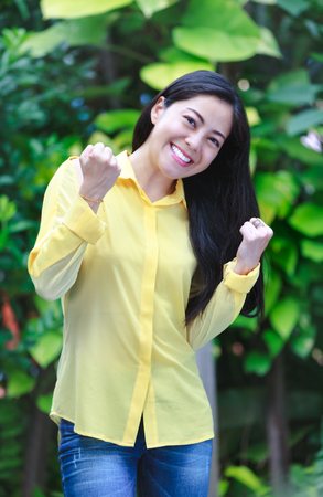 Asian woman smiling happy in park. Pretty young woman outdoors. Positive human emotion. Action of winner or successful people.の写真素材