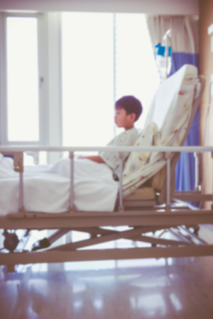 Abstract blurred background of illness asian child admitted at modern and comfortable equipped hospital room with infusion pump intravenous IV drip. Health care and people concept. Vintage style.の写真素材