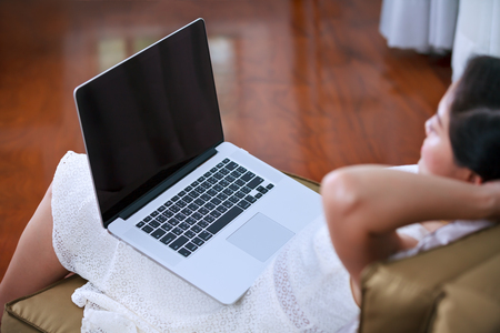 Beautiful asian woman resting and clasping her hands behind her nape of the neck with her eyes closed after work hard with laptop computer, side view.の写真素材