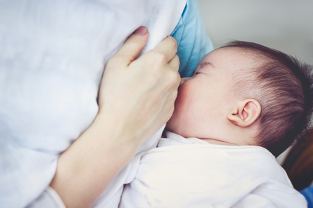Closeup portrait of mother breastfeeding her newborn baby with breast milk. Drinking milk for good health. Concept about the growth of children. Vintage tone.の写真素材