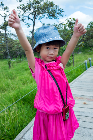 Adorable asian girl with camera at park . Child relaxing outdoors with bright sunlight at the day time, travel on vacation. Positive human emotion.の写真素材