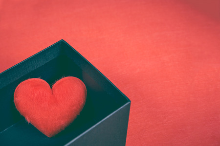 Red heart-shaped in a black gift box for a Valentine's day on red background, concept of love. Free space for your text.の写真素材