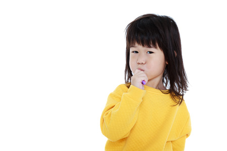 Closeup cute asian girl in pajamas with a toothbrush in hand and brush teeth, oral health concept. Isolated on white background. Sleepy chinese child waking up early in the morning.の写真素材