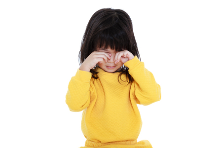 Chinese child waking up, girl looks sleepy in the morning, isolated on white background. A tired asian girl in pajamas rubbing eyes.の写真素材