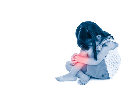 Sadness asian child barefoot sitting on floor with copy space. Girl hurt at shin, isolated on white background. Photo with color increase blue skin and red spot indicating location of pain.の写真素材