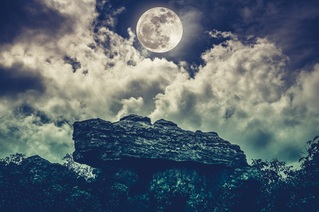 The perfect combination of boulder with sky background and beautiful full moon behind cloud. Outdoor at nighttime. Beauty of nature use as background.の写真素材
