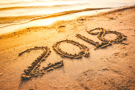Year 2018 handwritten on seashore sand with sea wave water. Concept of upcoming new year and passing of time.の写真素材