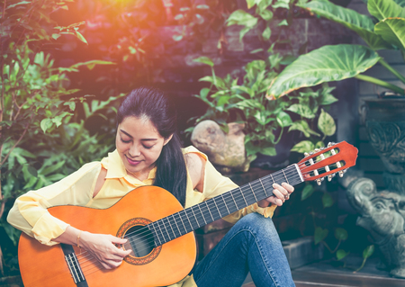 Pretty songwriter smiling and having fun enjoy hobby concept. Asian woman playing acoustic guitar,...