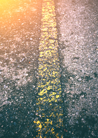 Perspective of asphalt texture road with yellow old marking line. Outdoor at daytime with bright sunlight on summer day.の写真素材