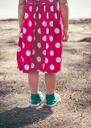 Back view of girl in red dress relaxing and enjoy the view, outdoor with sunlight at daytime on summer day. Travel on vacation. Concept of young connecting children with nature. Vintage effect tone.の写真素材