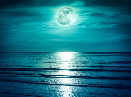 Landscape of green sky with dark cloudy and bright full moon over seascape in the evening. Serenity nature background, outdoor at nighttime. The moon taken with my own camera.の写真素材
