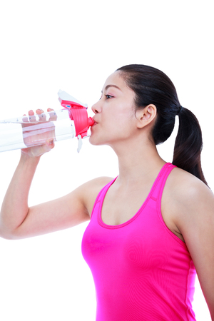 Asian beautiful woman in pink yoga outfit drinking fresh water form water bottle after doing fitness exercise at studio. Healthy lifestyle concept.  Isolated on white background.の写真素材