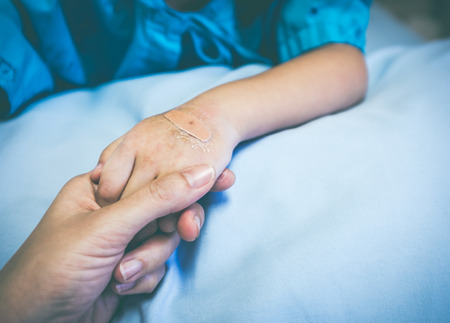 Closeup hand of parent holding child's patient hand for encouragement and empathy. Plaster on hand...
