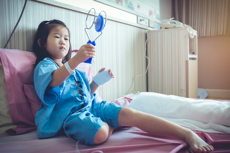 Illness asian child with saline intravenous (IV) on her hand while admitted in hospital . Health care stories. Vintage film filter effect.の写真素材