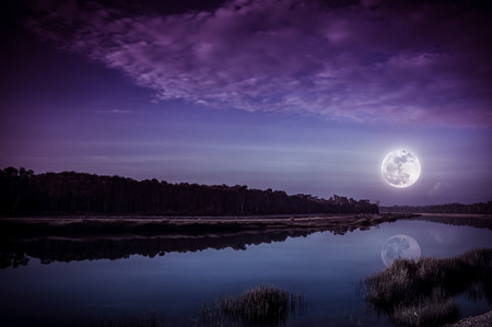 Beautiful landscape of purple sky with cloud and full moon above silhouettes of trees at riverside. Serenity nature background, outdoor at nighttime. The moon taken with my camera.の写真素材