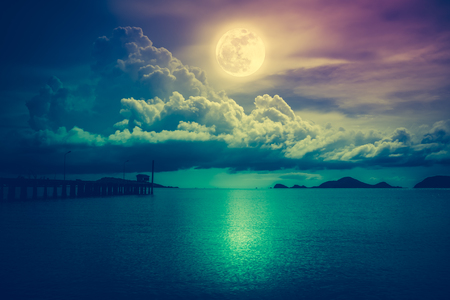 Beautiful landscape view of the sea. Colorful sky with clouds and bright full moon on seascape to night. Serenity nature background, outdoor at nighttime. Cross process. The moon taken with my own camera.の写真素材