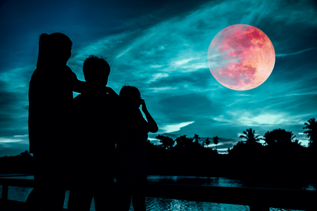 Silhouette of mother and children looking at red super moon or blood moon on colorful sky with cloud. Serenity nature background. Happy family spending time together. The moon taken with my camera.の写真素材