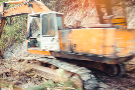 Blurred background. Yellow backhoe or excavator equipment for removing earth on construction site.