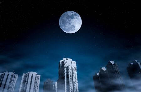Cityscape at night time with fogy and darkness blue sky super moon full of many stars.の写真素材