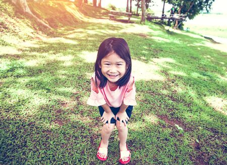 Portrait of a smiling little asian girl on green grass in the park.の写真素材