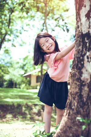 Cute little asian girl under big tree outdoor in the park.の写真素材